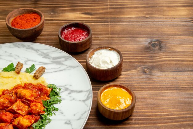 Vista frontal de sabrosas rebanadas de carne con puré de papas y condimentos en el escritorio marrón, plato, carne, papa, comida, pan