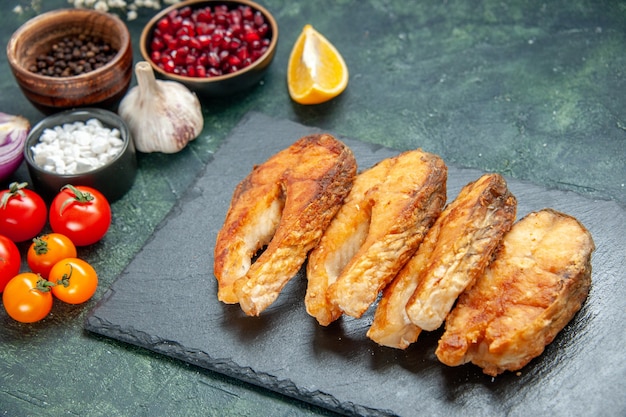 Vista frontal sabroso pescado frito con tomates y condimentos en la superficie oscura comida marisco plato ensalada mariscos freír cocinar carne