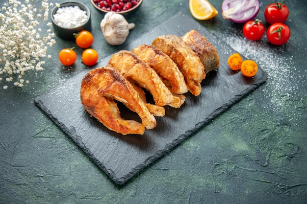 Vista frontal sabroso pescado frito con tomates en la superficie azul oscuro comida plato de pimienta freír mariscos ensalada de comida de carne de mar