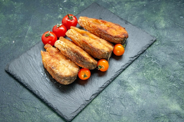 Vista frontal sabroso pescado frito con tomates en la superficie oscura comida comida pimienta carne freír mariscos ensalada de mar plato cocinar