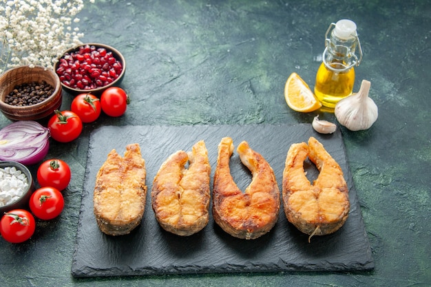 Vista frontal sabroso pescado frito con tomates en la superficie oscura plato de cocina comida ensalada freír comida mariscos pimienta carne de mar