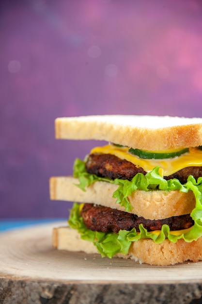 Vista frontal sabroso sándwich de carne con ensalada verde en la mesa de colores