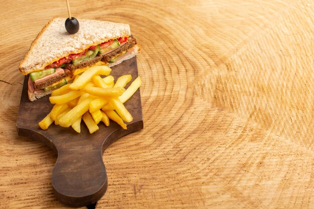 Vista frontal sabroso sándwich con jamón de oliva tomates verduras con papas fritas en madera