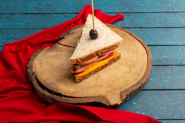 Vista frontal sabroso sándwich con jamón de queso dentro de un escritorio de madera azul