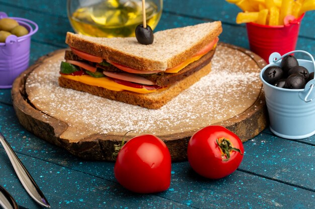 Vista frontal sabroso sándwich de pan tostado con jamón de queso dentro con aceitunas papas fritas aceite de tomates en azul