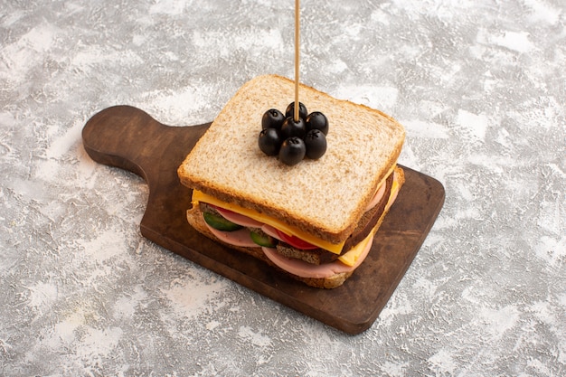 Vista frontal sabroso sándwich con tomates jamón oliva verduras en palo