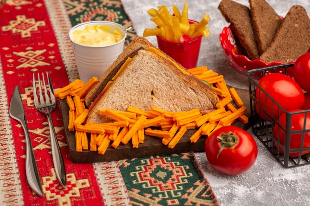 Vista frontal sabroso sándwich de tostadas con jamón de queso junto con papas fritas tomates crema agria en blanco