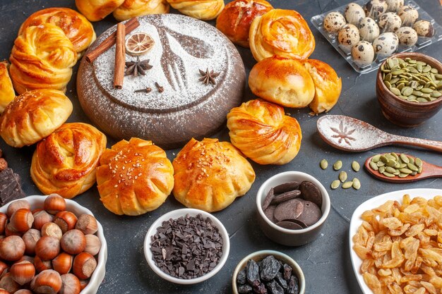 Vista frontal sabrosos bollos dulces con nueces y pasas en superficie oscura