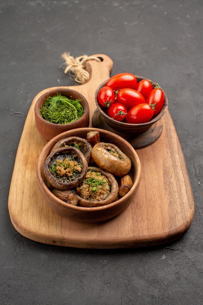Vista frontal sabrosos champiñones cocidos con tomates frescos en la mesa oscura comida salvaje madura