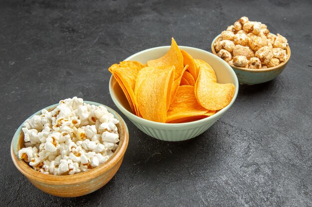 Vista frontal sabrosos cips de queso con diferentes bocadillos en el fondo oscuro