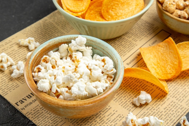 Vista frontal de sabrosos cips de queso con diferentes bocadillos para el tiempo de la película sobre fondo oscuro