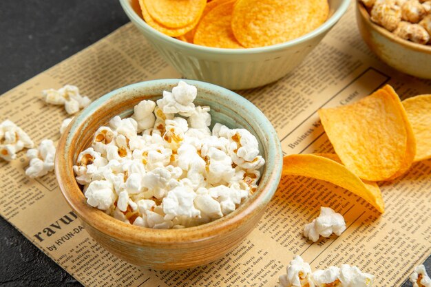 Vista frontal de sabrosos cips de queso con diferentes bocadillos para el tiempo de la película sobre fondo oscuro