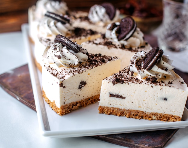 Vista frontal sabrosos pasteles de queso oreo dentro de un plato blanco sobre la superficie marrón