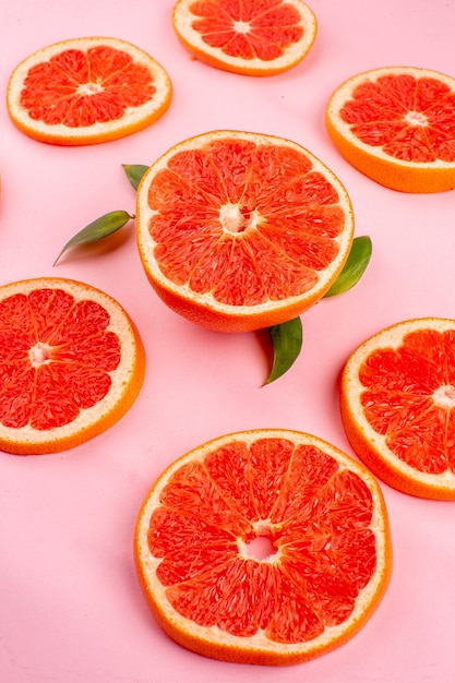 Foto gratuita vista frontal de sabrosos pomelos en rodajas de frutas jugosas forradas en una mesa rosa