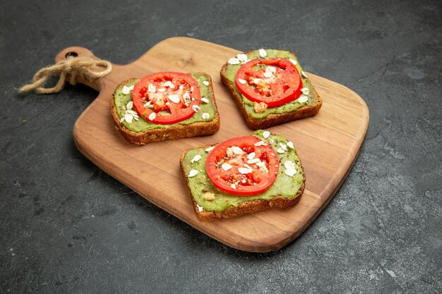 Vista frontal sabrosos sándwiches de aguacate con tomates rojos en rodajas