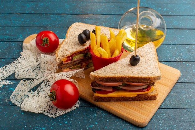 Vista frontal sabrosos sándwiches con jamón de oliva tomates papas fritas aceite y toamtoes en madera