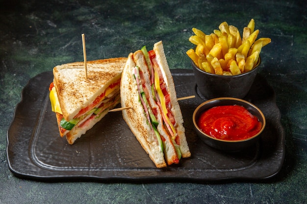 Vista frontal sabrosos sándwiches de jamón con papas fritas superficie oscura