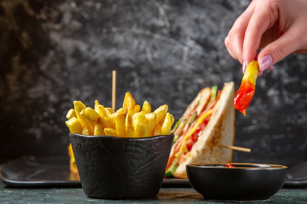 Vista frontal sabrosos sándwiches de jamón con papas fritas superficie oscura