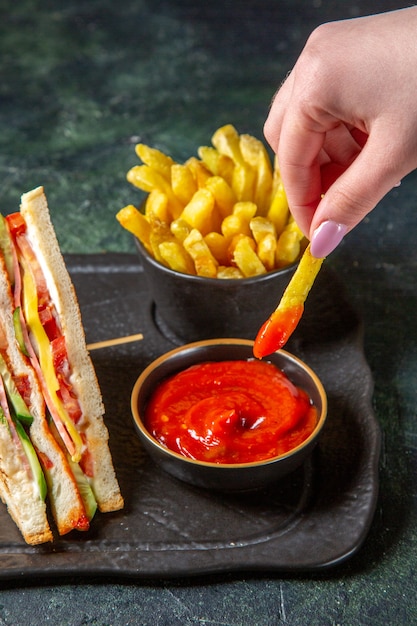 Vista frontal sabrosos sándwiches de jamón con papas fritas superficie oscura