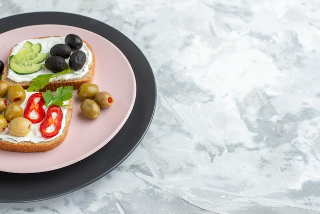 Vista frontal sabrosos sándwiches con pepinos y aceitunas dentro de la placa blanca