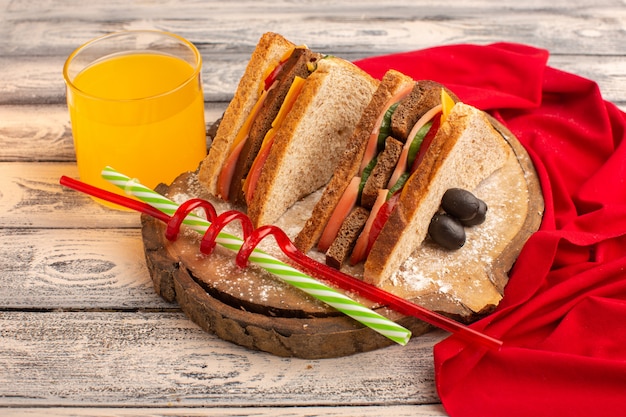 Foto gratuita vista frontal sabrosos sándwiches de tostadas con jamón de queso dentro junto con jugo en madera