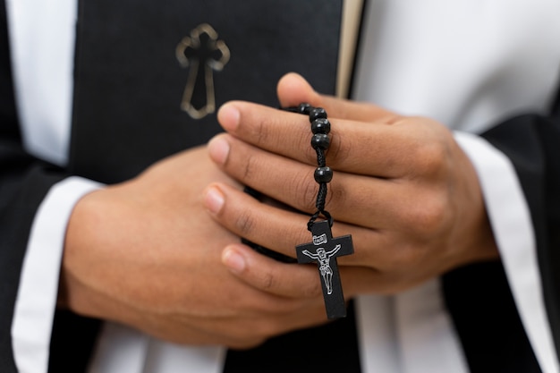 Vista frontal sacerdote sosteniendo pequeña cruz