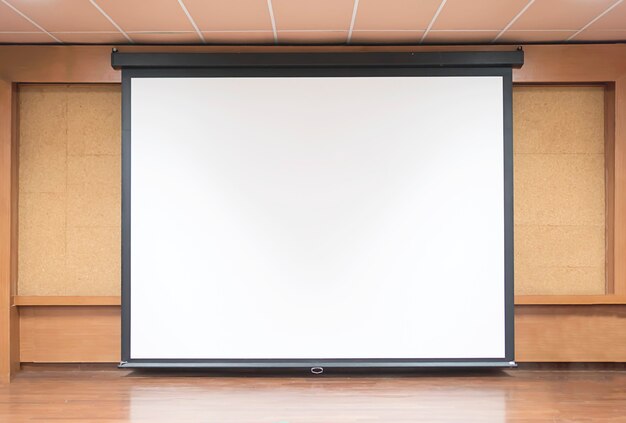 Vista frontal de la sala de conferencias con pantalla de proyector blanca vacía