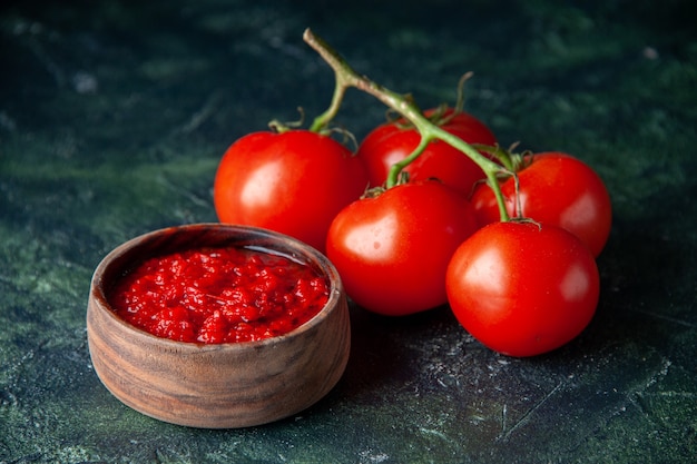 Vista frontal de la salsa de tomate con tomates rojos frescos en la superficie oscura de color rojo tomate condimento pimienta sal