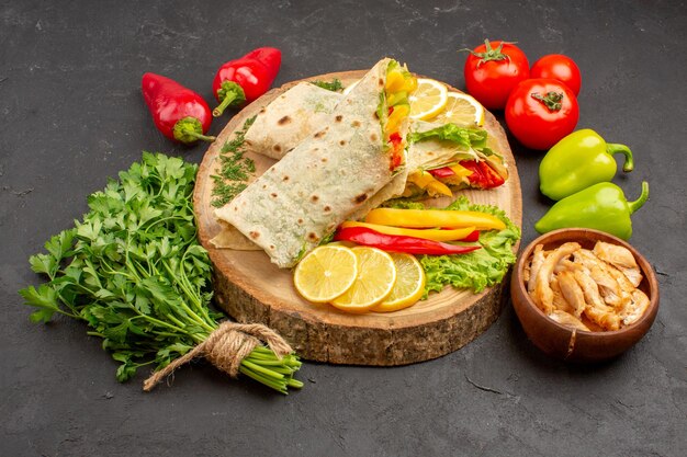 Vista frontal sándwich de carne shaurma en rodajas con rodajas de limón y verduras en el espacio oscuro