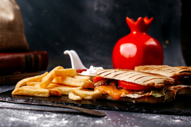 Vista frontal sándwich en rodajas junto con papas fritas en el piso gris