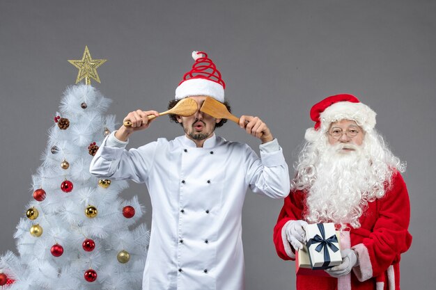 Vista frontal de santa claus alrededor del árbol de vacaciones con cocinero masculino