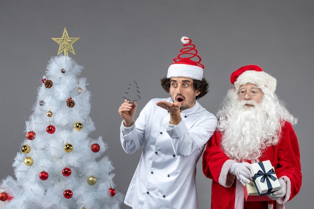 Vista frontal de santa claus alrededor del árbol de vacaciones con cocinero masculino