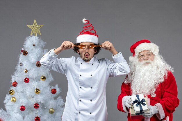 Vista frontal de santa claus alrededor de atributos de vacaciones con cocinero masculino