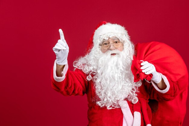 Vista frontal de santa claus con bolsa llena de regalos en la fiesta roja de año nuevo