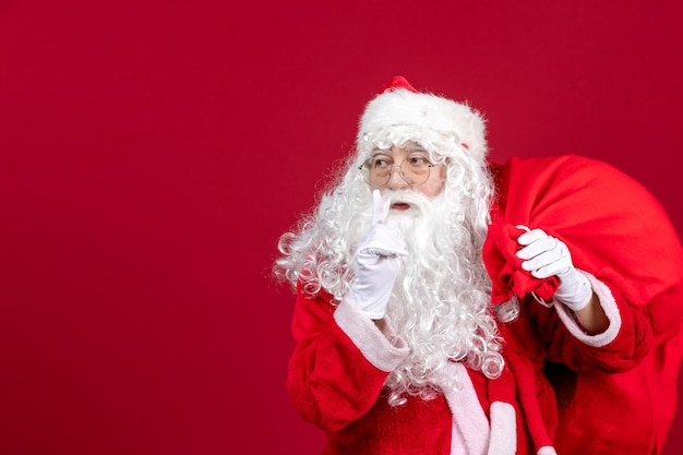 Vista frontal de santa claus con bolsa llena de regalos en rojo vacaciones año nuevo emoción navideña