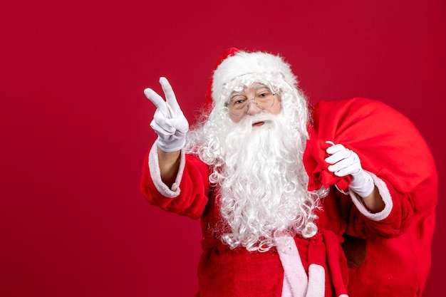 Vista frontal de santa claus con bolsa llena de regalos en vacaciones rojas año nuevo emoción navideña