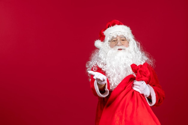 Vista frontal de santa claus con bolsa roja llena de regalos en la emoción de año nuevo de navidad de vacaciones rojas