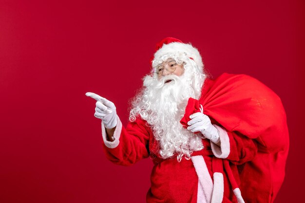 Vista frontal de santa claus con bolsa roja llena de regalos en rojo navidad emociones vacaciones de año nuevo