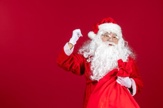 Vista frontal de santa claus con bolsa roja llena de regalos en vacaciones de año nuevo rojo emoción navideña