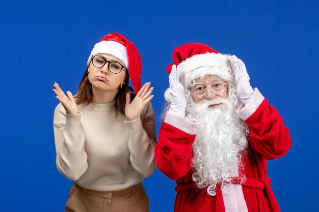 Vista frontal de santa claus con bonita mujer de pie sobre la nieve de color azul emoción de año nuevo de navidad