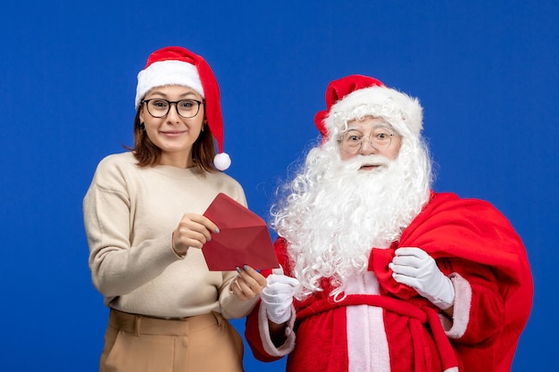 Vista frontal de santa claus y carta de apertura de mujer joven en color azul de año nuevo de navidad de vacaciones