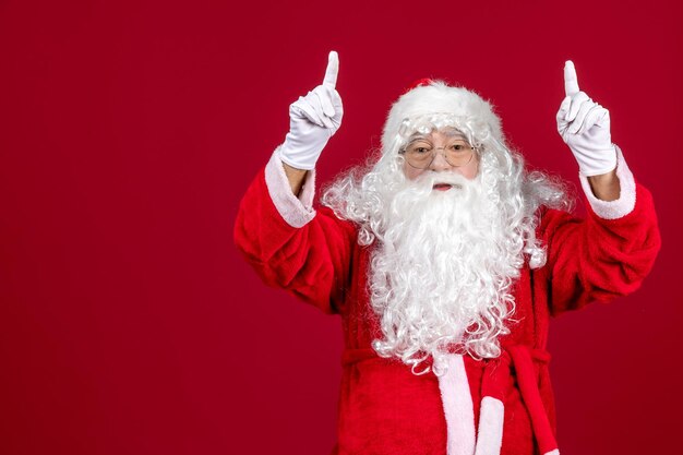 Vista frontal de santa claus con clásico oso blanco y ropa roja en piso rojo vacaciones año nuevo emociones navideñas