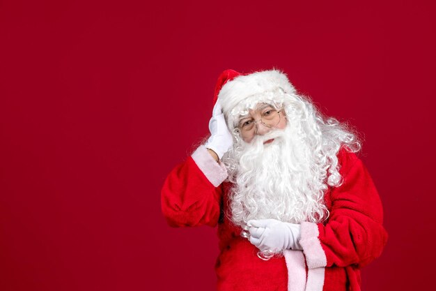 Vista frontal de santa claus con el clásico oso blanco y ropa roja en el piso rojo vacaciones navidad año nuevo emociones