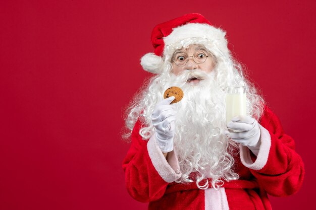 Vista frontal de santa claus comiendo galletas y bebiendo leche