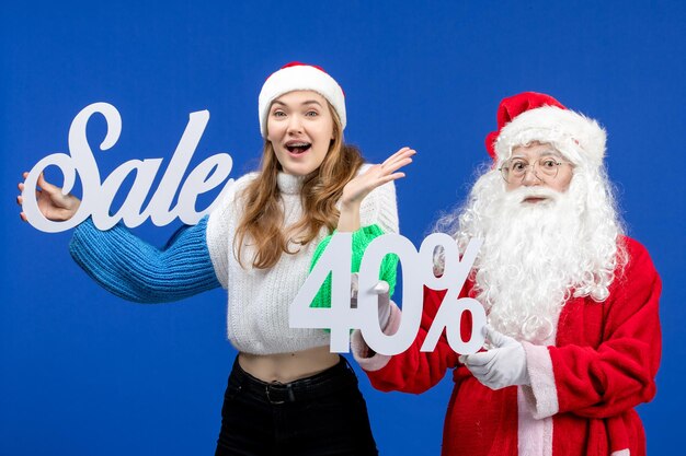 Vista frontal de santa claus con escritura de venta de explotación femenina en la nieve de año nuevo de navidad fría de vacaciones azules