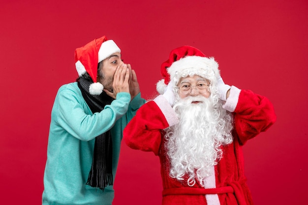 Vista frontal de santa claus con hombre interactuando en rojo presente navidad emoción vacaciones año nuevo