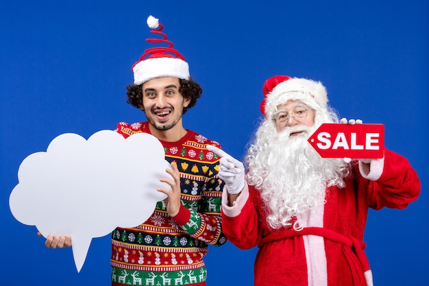 Vista frontal de santa claus con hombre joven con cartel blanco y escritura de venta