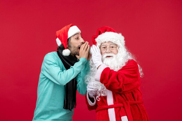 Vista frontal de santa claus con hombre parado en rojo presenta vacaciones de emoción navideña