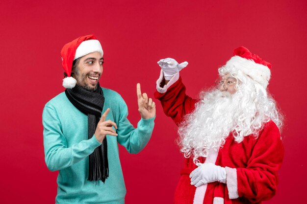 Vista frontal de santa claus con hombre parado en rojo presente navidad emoción vacaciones