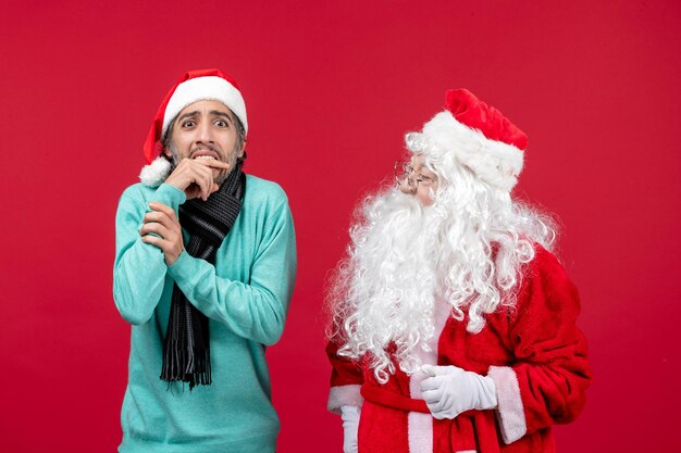 Vista frontal de santa claus con hombre de pie en la emoción de navidad de vacaciones presente rojo